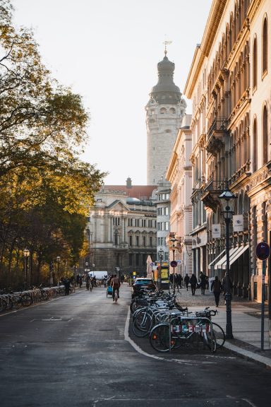 Schillerstraße mit Fahrrädern, Deutscher Bank und Turm vom neuen Rathaus im Hintergrund bei Sonnenuntergang.