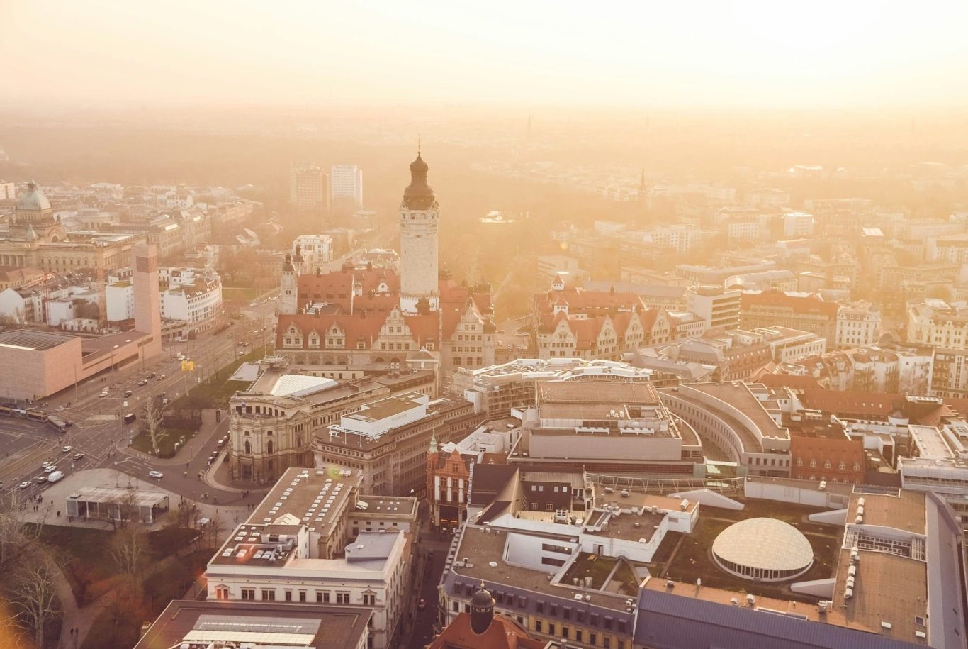 Blick auf die Stadt Leipzig bei Sonnenaufgang mit Neuem Rathaus und moderner Architektur.
