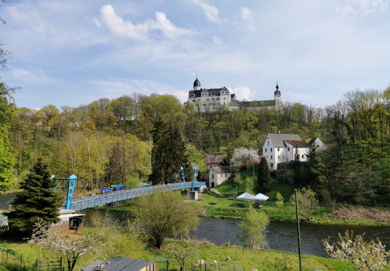 Überblick auf eine malerische Landschaft mit Schloss, Brücke und einem Fluss.