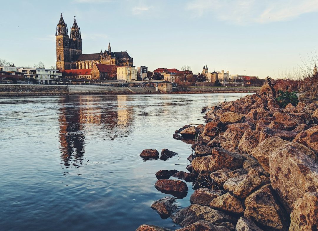 Blick auf die Stadt mit einer Kirche am Ufer eines ruhigen Flusses.