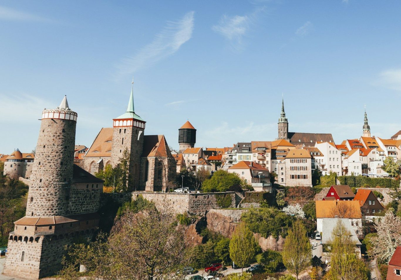 Historische Stadtansicht mit Burgen, Häusern und blauem Himmel.